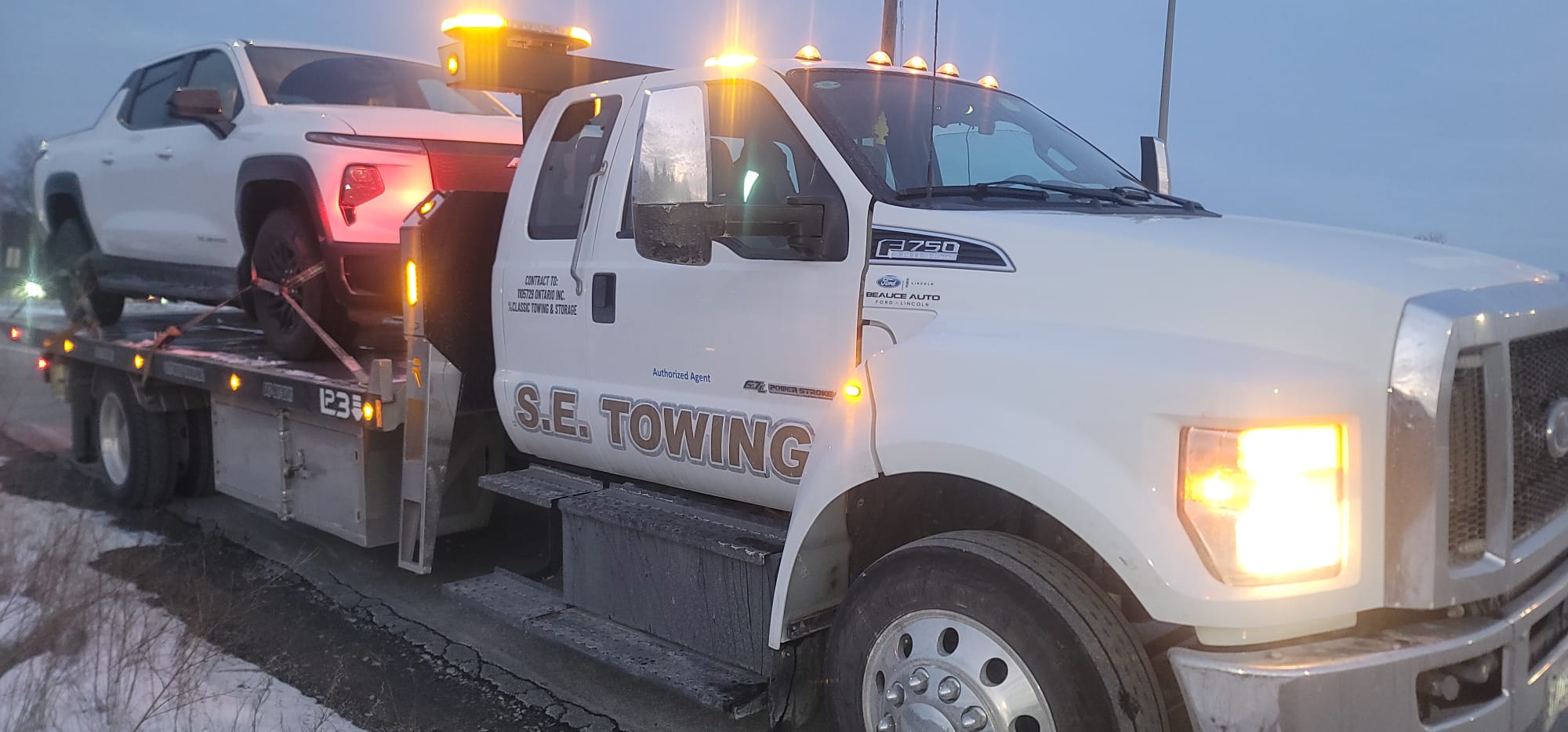 Red Hyster forklift secured on S.E. Towing flatbed on a snowy road