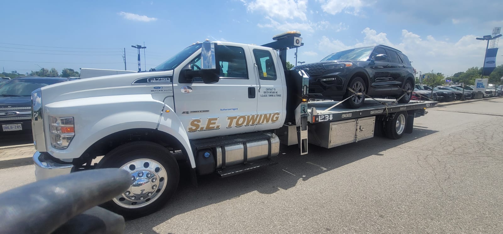 S.E. Towing F-750 flatbed with a black Ford Explorer at a Ford dealership in Durham Region