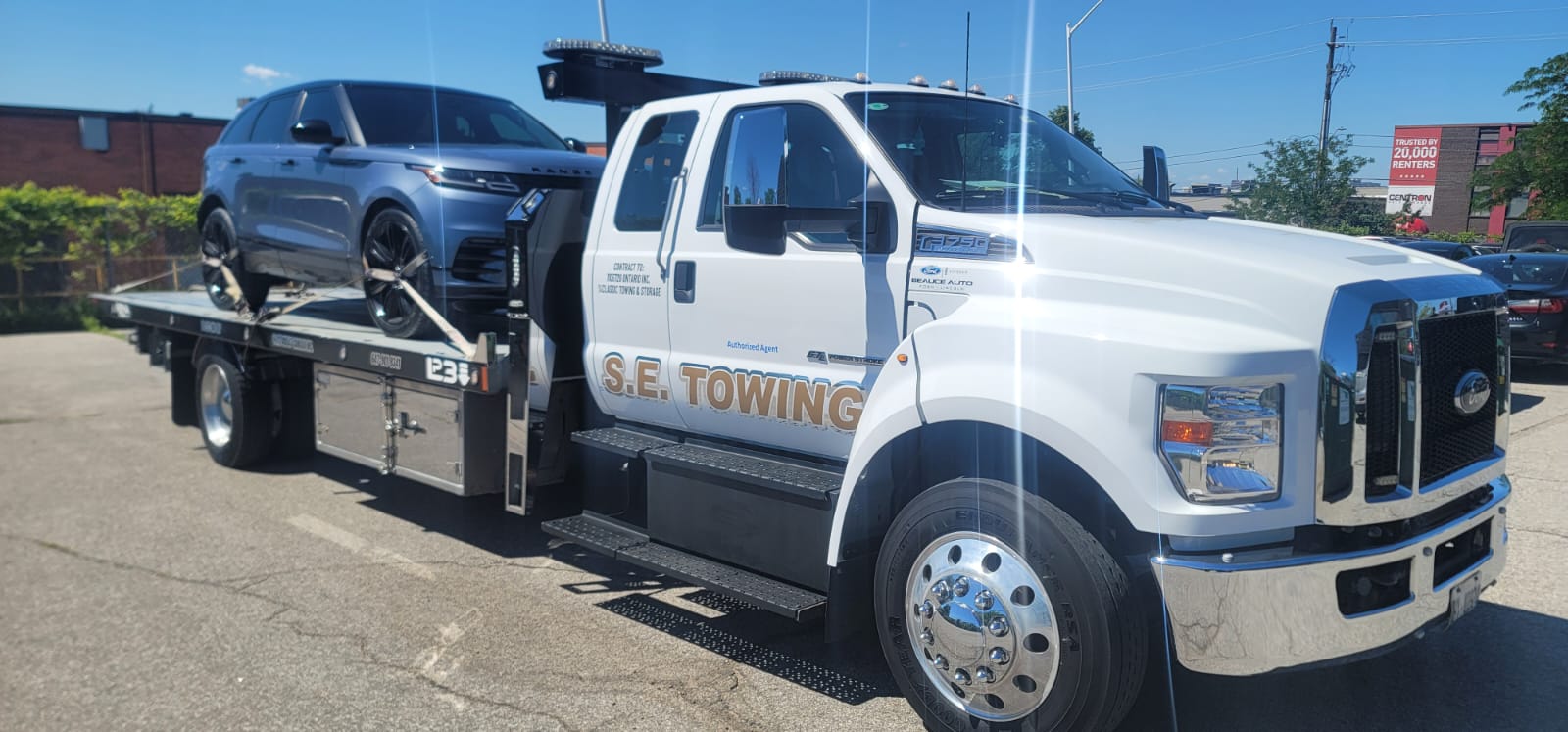 S.E. Towing F-750 flatbed carrying a Range Rover on a sunny Whitby street