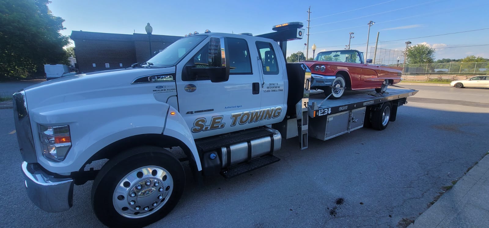 S.E. Towing F-750 with a classic red Thunderbird convertible parked lakeside