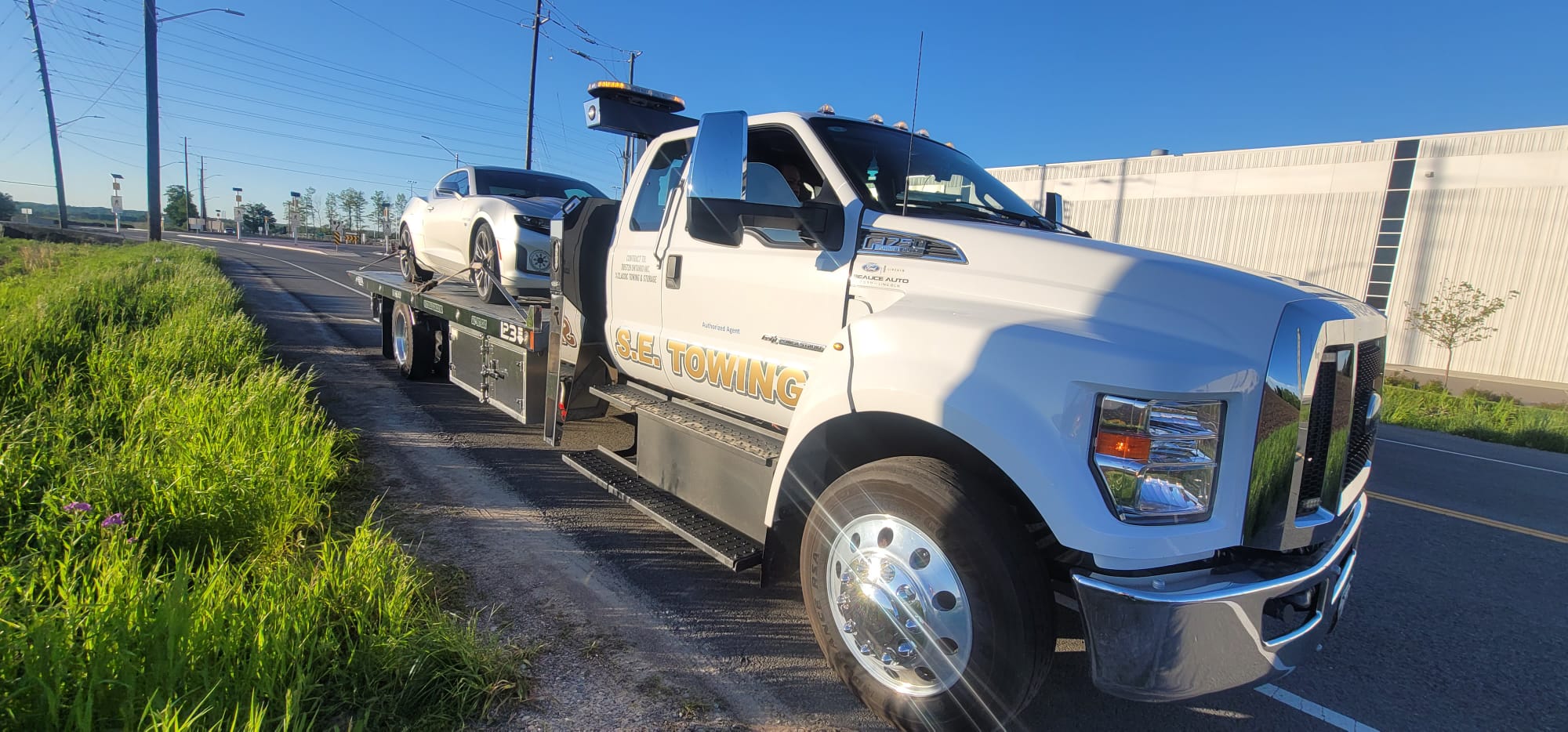 S.E. Towing F-750 transporting a silver Chevrolet Camaro on the highway