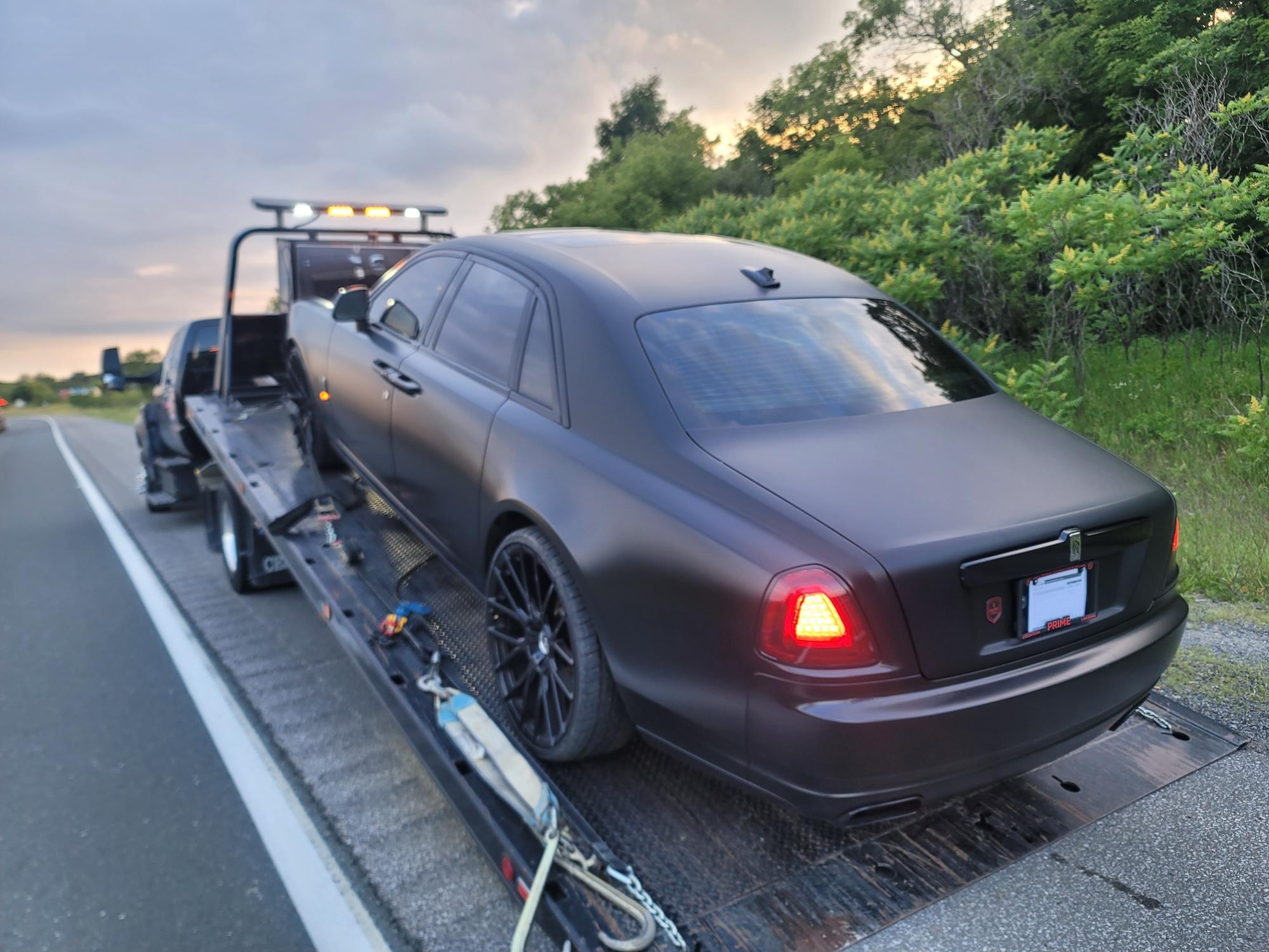 Matte black Rolls-Royce on flatbed at sunset