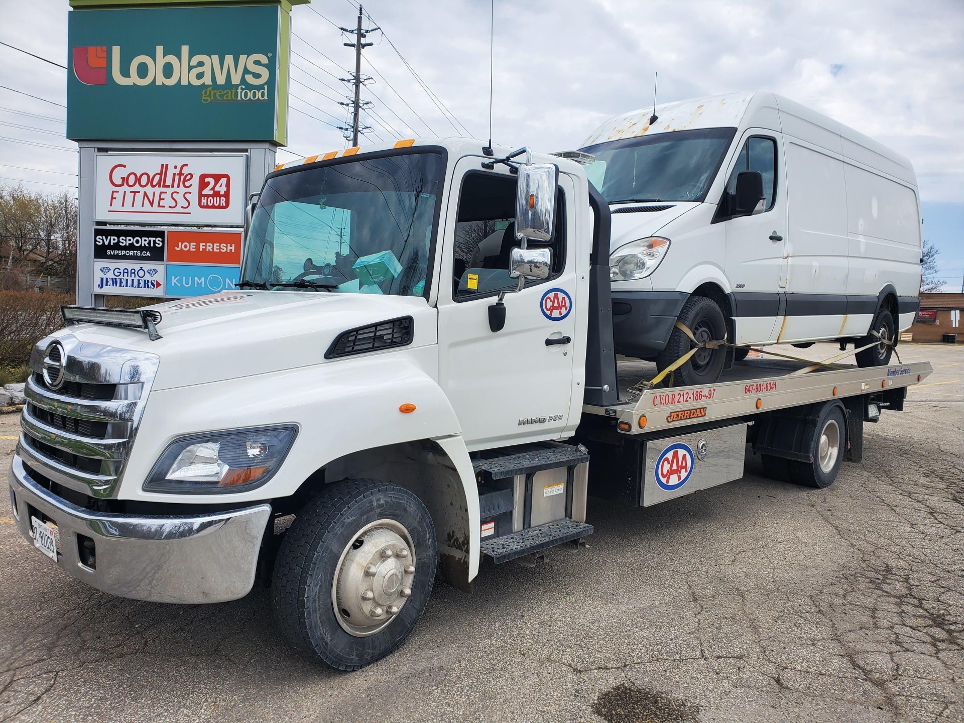 Hino flatbed loaded with a Mercedes Sprinter van outside Loblaws